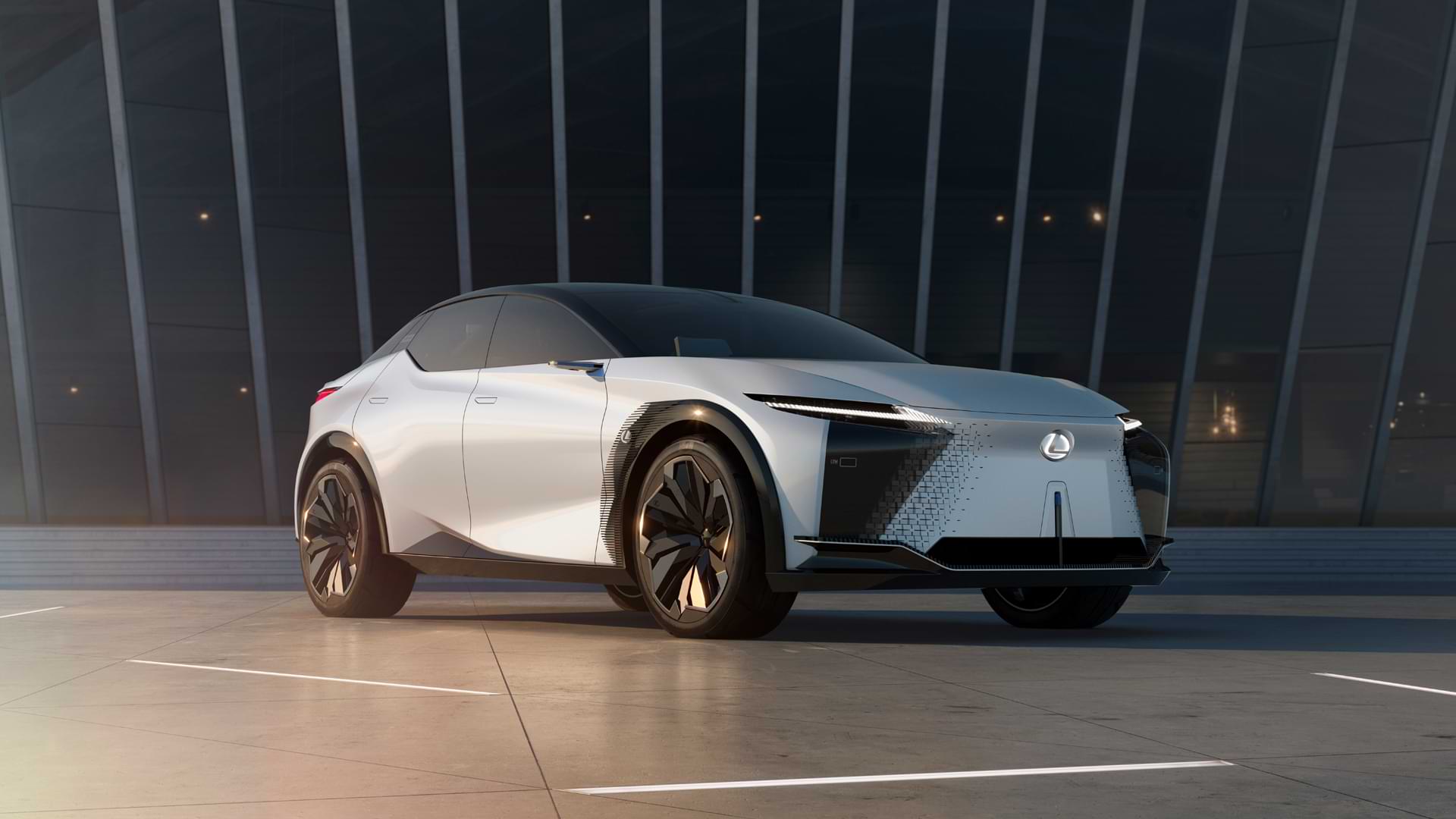 A white Lexus concept LF-Z sits stationary on lit up ground. 