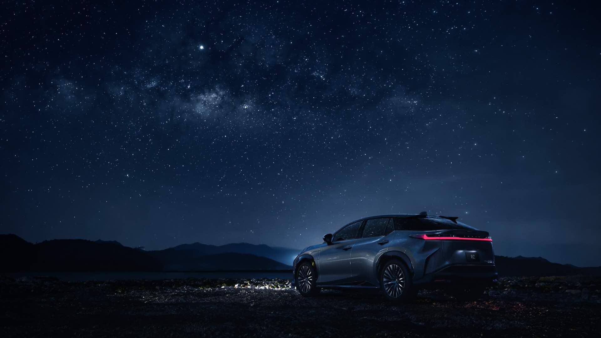 RZ on a dirt track lit up by moonlight and stars. It's headlights are illuminated. 